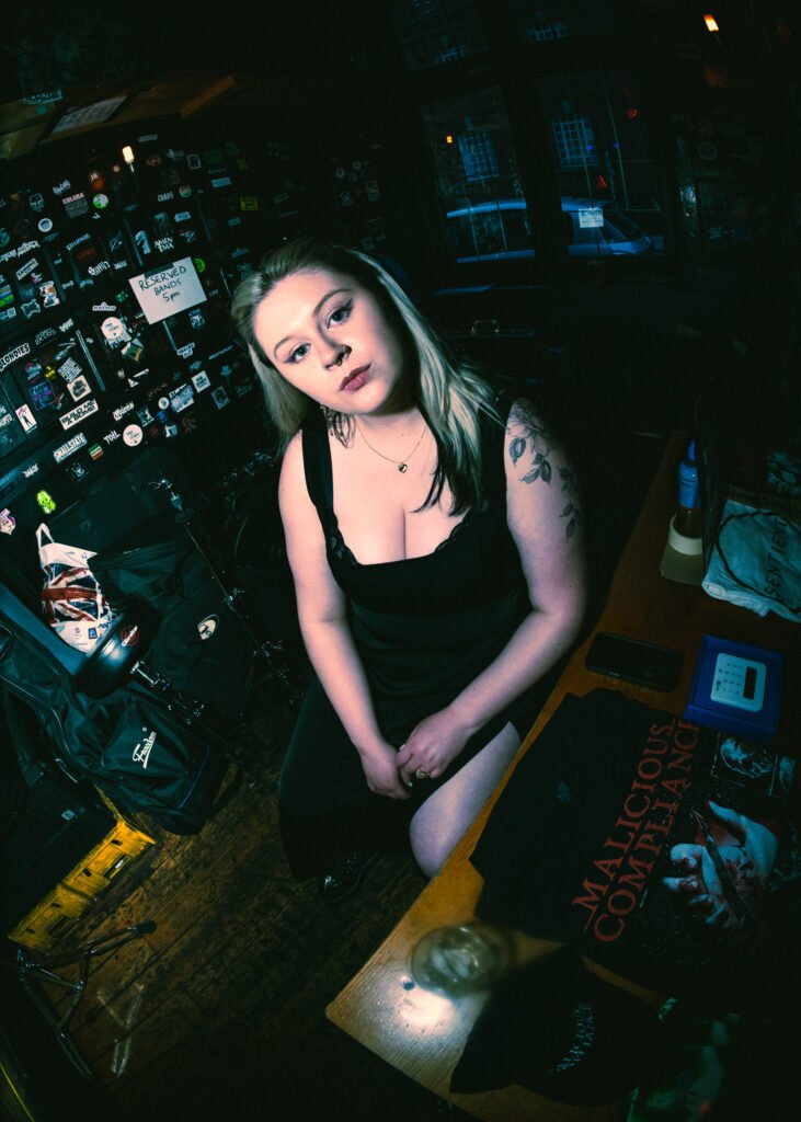 Woman wearing a black dress in a music venue.