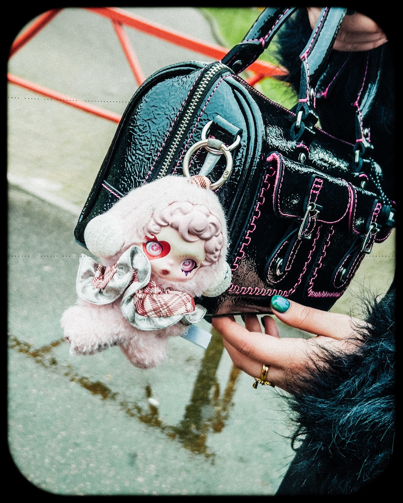 Black buckled bag with a pink plush charm.